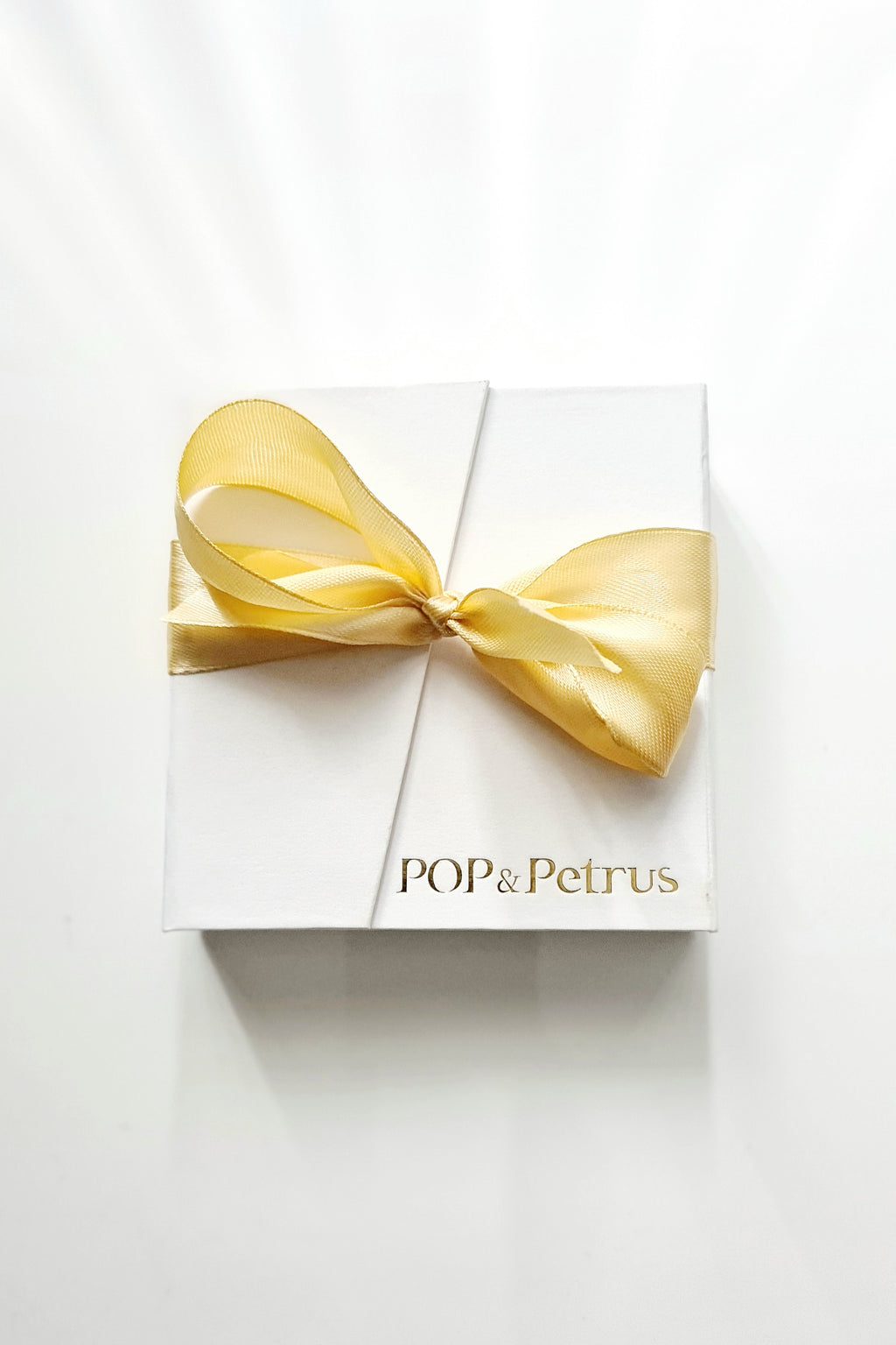 White gift box with a gold ribbon and 'POP & Petrus' branding on a white background